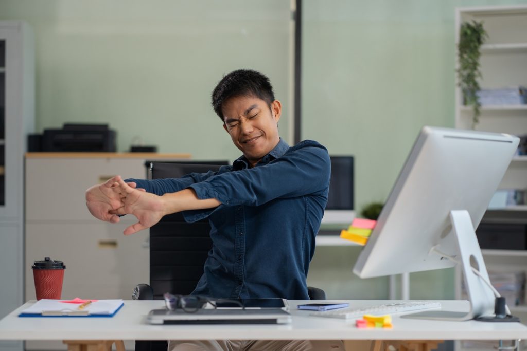 Male businessman is doing a stretchy posture due to sitting in t